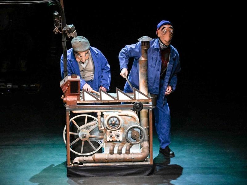 Marionnettes de deux ouvriers devant une usine