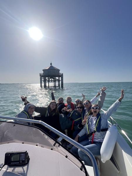 Des jeunes filles sur le bateau à moteur, devant le phare du Bout du Monde.