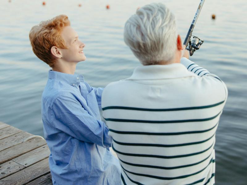 Un grand père et son petit fils pêche au bord de l'eau